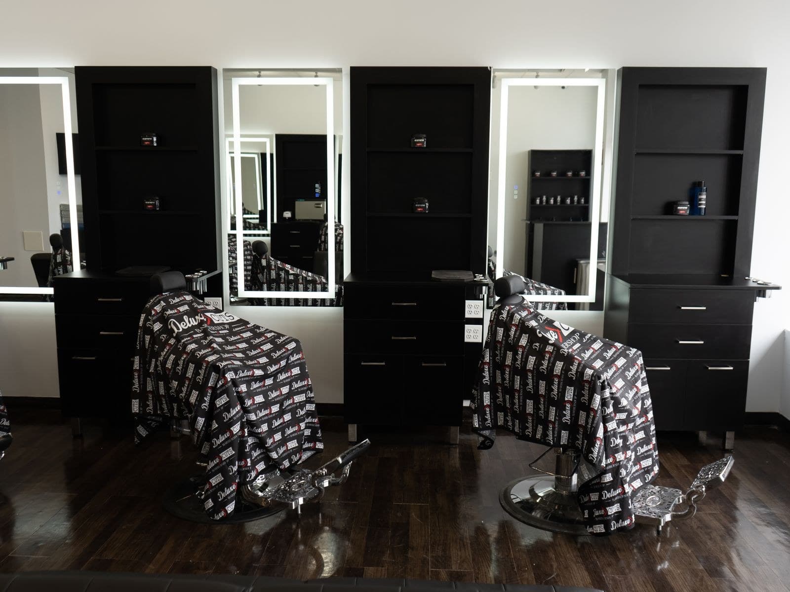 Row of black barber chairs with backlit mirrors